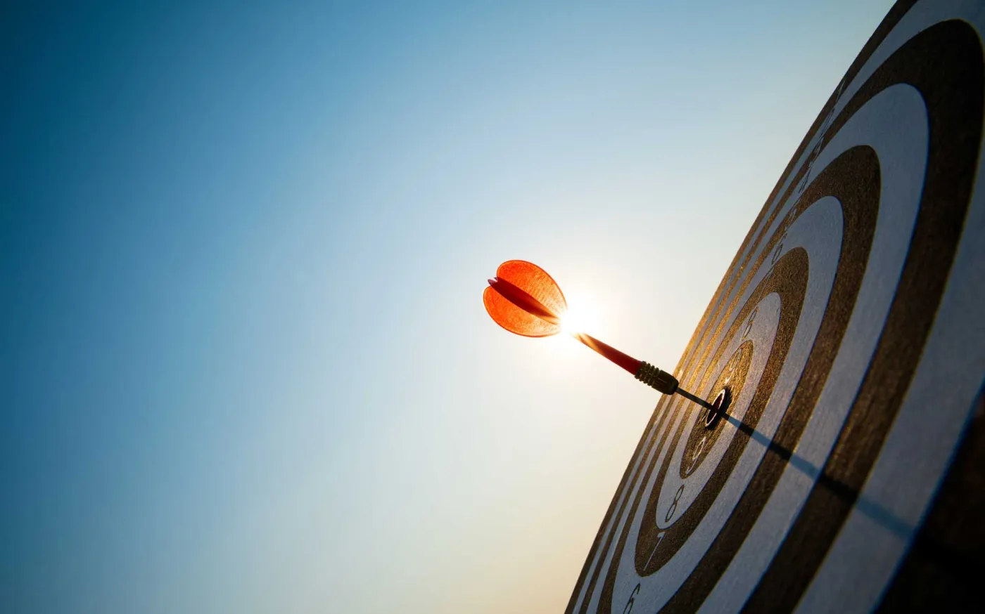 Close up shot red darts arrows in the target center on dark blue sky background